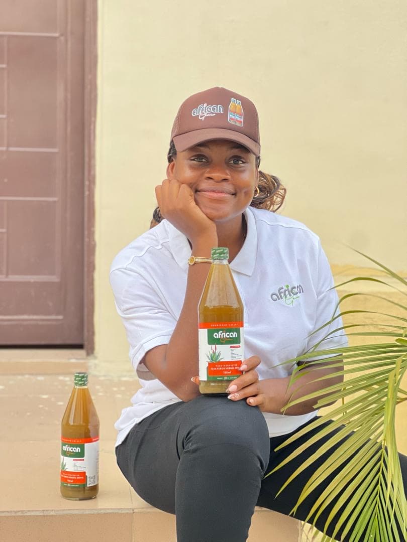 An African Gem distributor in branded cap and polo, holding the 750ml Aloe Ferox drink